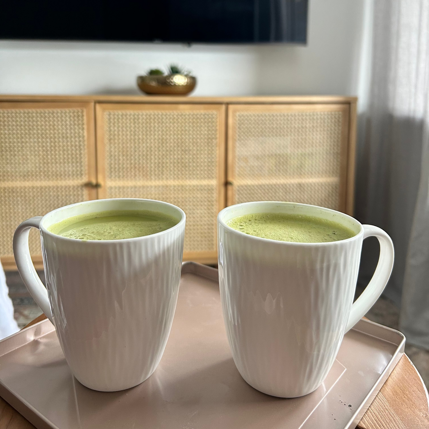 Two ceramic mugs containing matcha latte